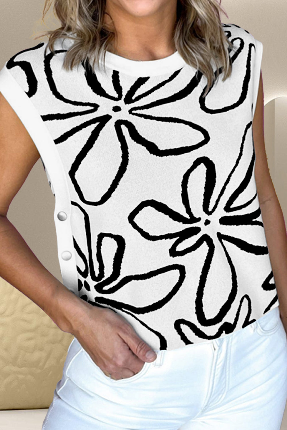 White knit top with black floral print and button detail on the side.