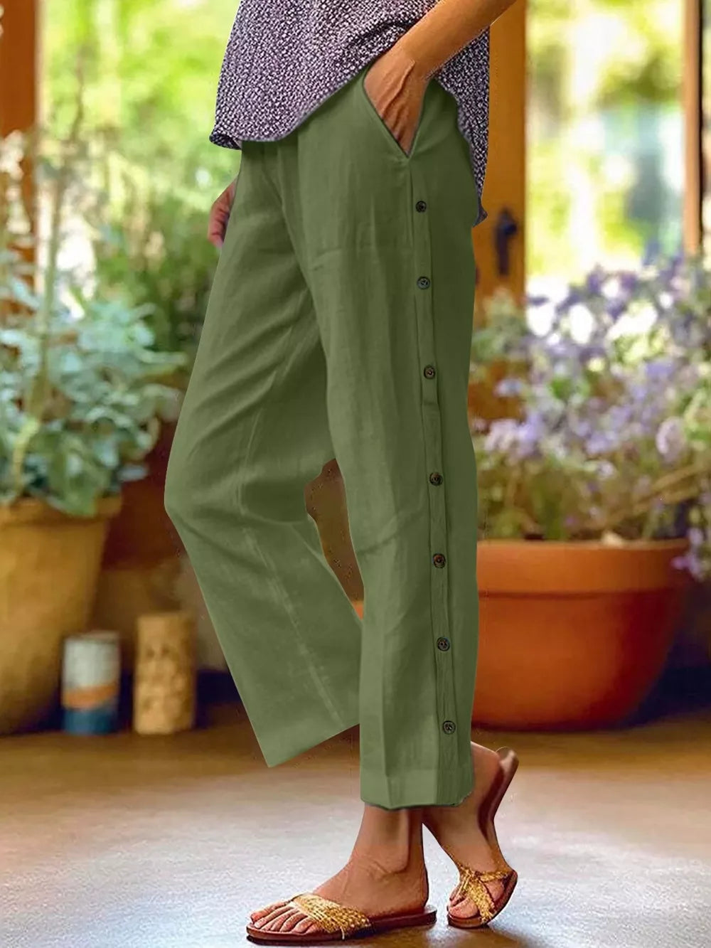 Green relaxed fit pants with decorative buttons down the side and pockets.