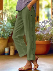 Green relaxed fit pants with decorative buttons down the side and pockets.