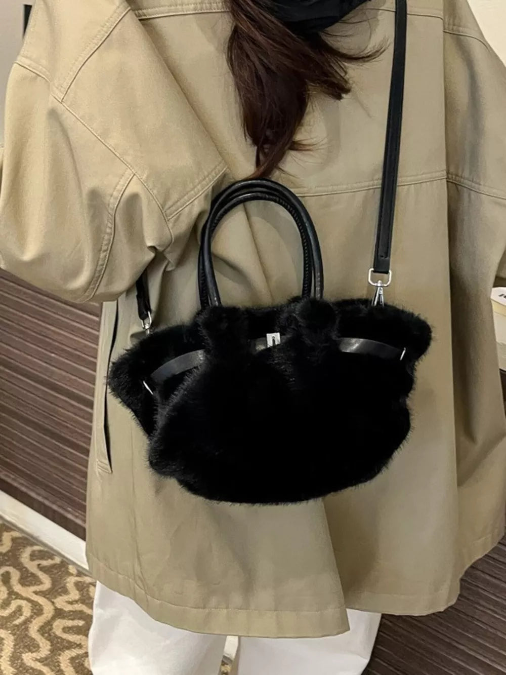 Black plush crossbody bag with chic buckle detail and leather handles.