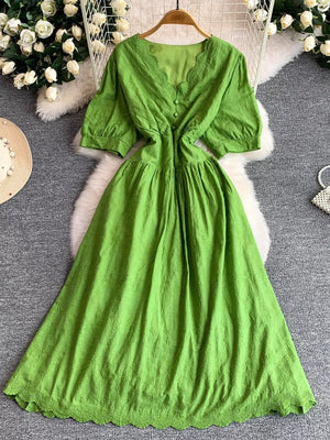 Green lace-embellished midi dress with V-neck, button front, and puff sleeves.