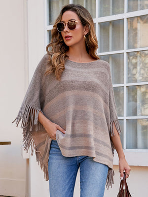 Striped fringe poncho in tan and grey with boat neck, styled with jeans.