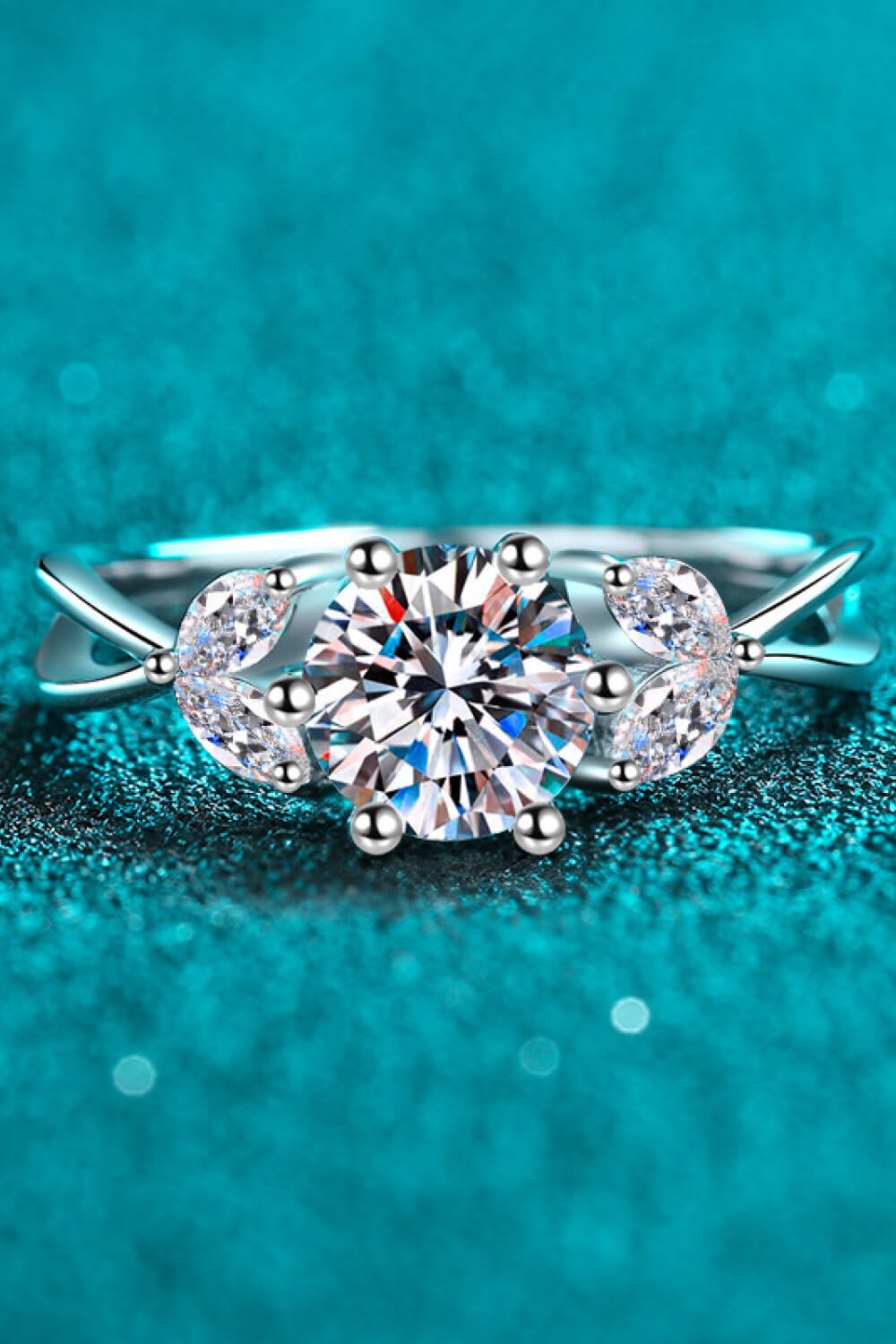 Silver moissanite ring with a large round center stone and leaf-shaped accents.