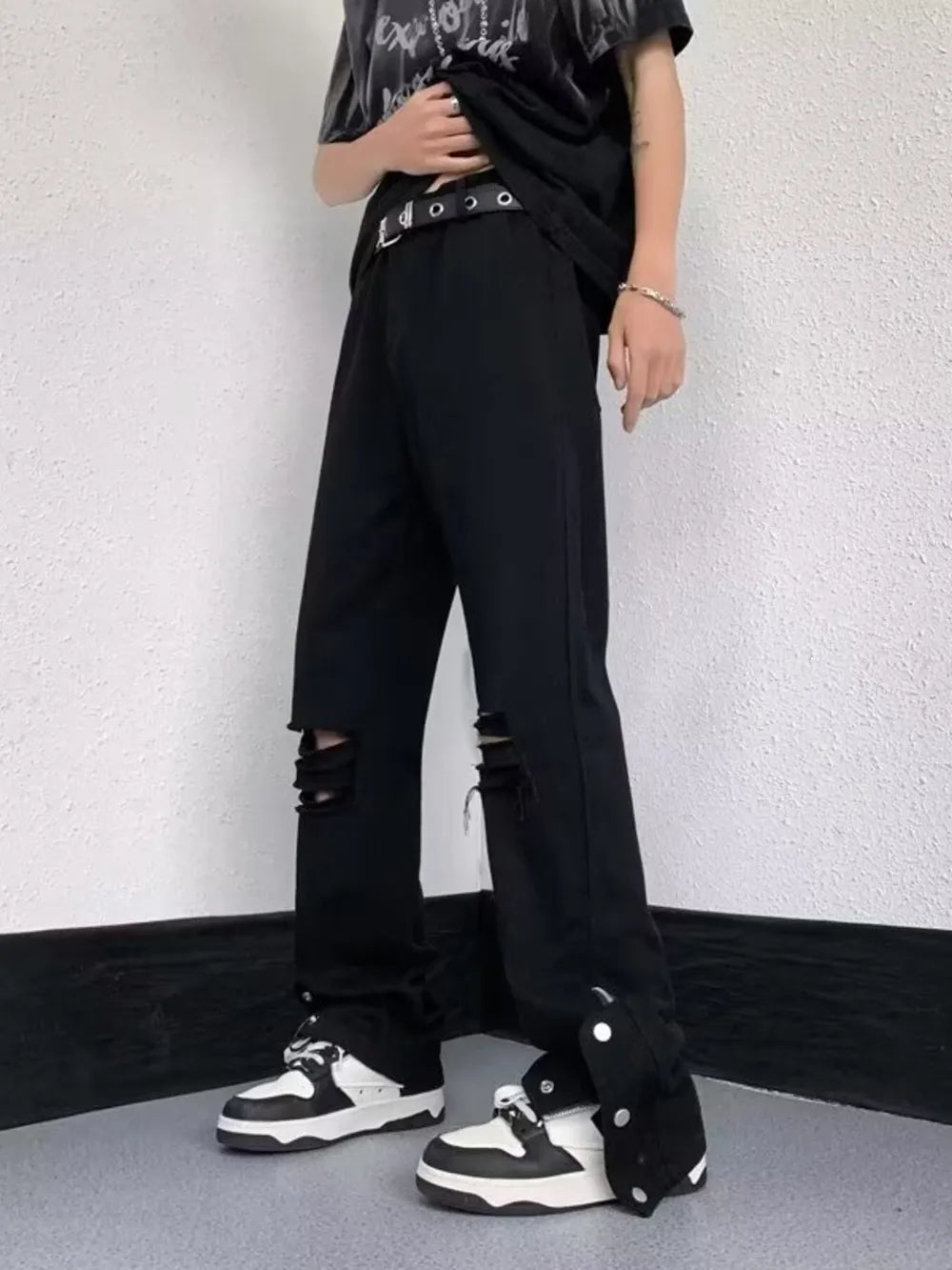 Black distressed loose-fit jeans with snap detail on the hem.