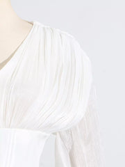 White mini dress with ruffled shoulder detail and sheer balloon sleeves.