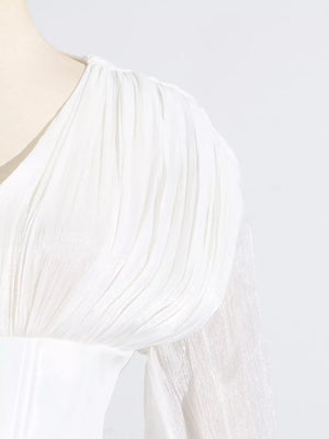 White mini dress with ruffled shoulder detail and sheer balloon sleeves.