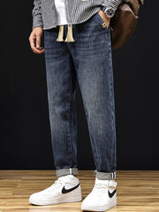 Men's relaxed fit medium wash denim jeans with drawstring and cuffed hems.