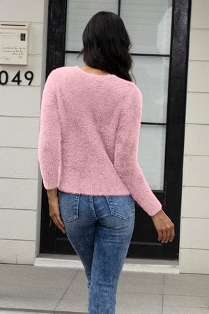 Pink fluffy knit sweater with crew neck and long sleeves, styled with jeans.