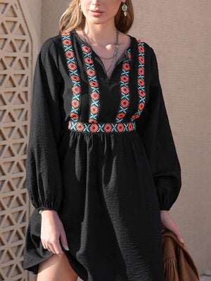 Black mini dress with embroidered yoke and waistband, V-neck, long sleeves.