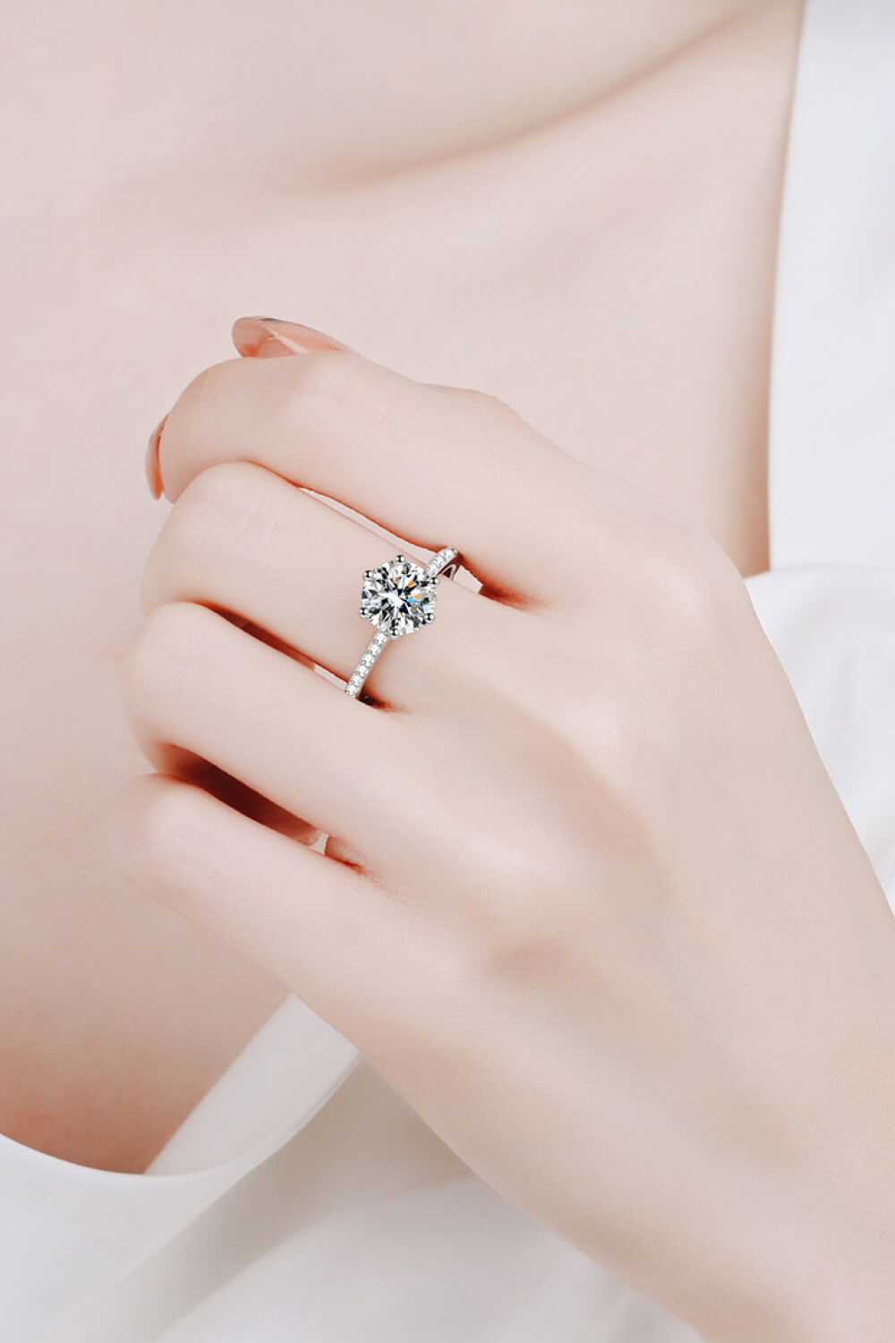 Silver moissanite ring with a round-cut center stone and pave band.