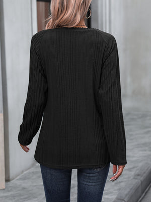 Black ribbed knit raglan sweater with long sleeves and button trim detail.