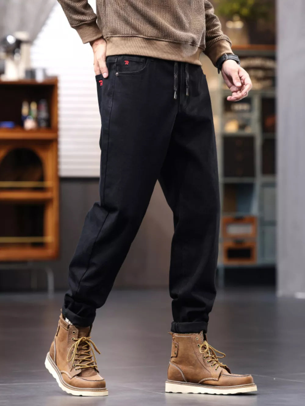 Men's black relaxed fit drawstring jeans with red pocket detail.