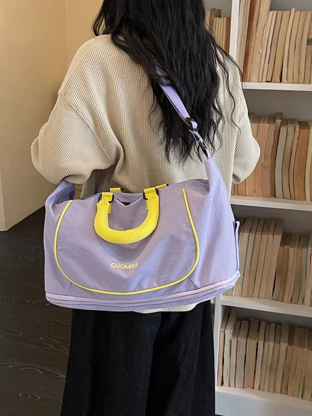 Purple Oxford cloth duffle bag with yellow handles and trim, worn over the shoulder.