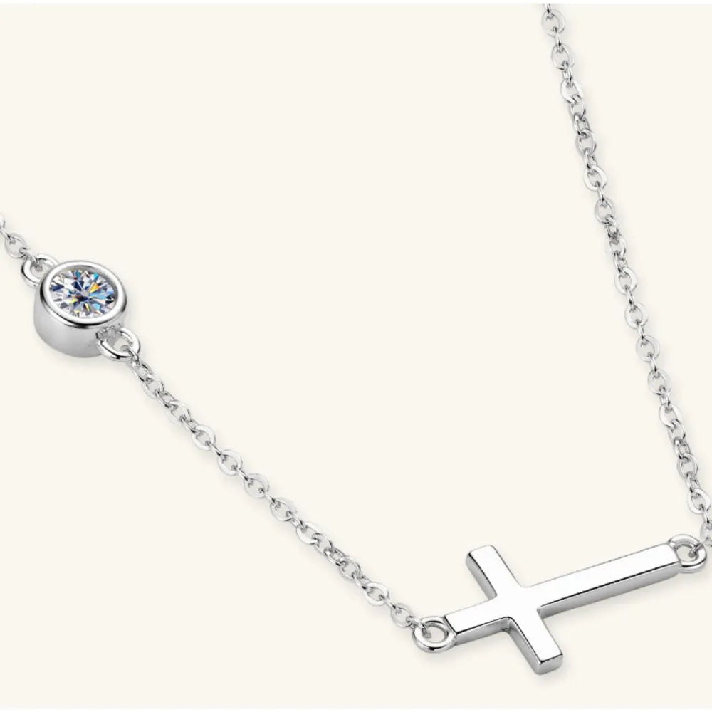 Silver asymmetrical cross pendant necklace with a single bezel-set crystal accent.
