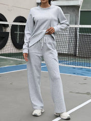 Light gray sweatpants with drawstring waist and wide leg, part of a two-piece set.