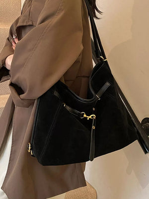 Black slouchy crossbody bag with gold hardware and adjustable strap.