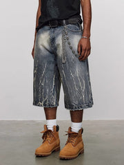 Men's loose fit denim shorts in washed blue with distressed details and a chain belt.