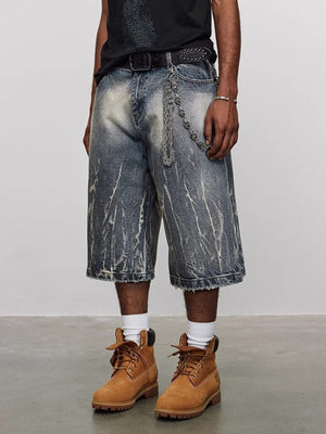 Men's loose fit denim shorts in washed blue with distressed details and a chain belt.