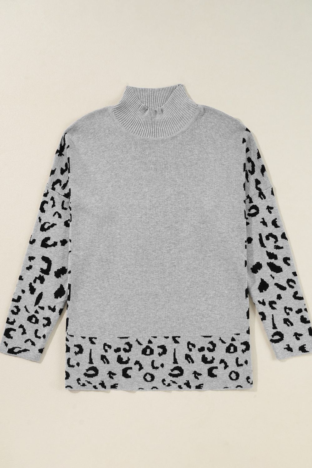 Gray knit sweater with mock neck and asymmetric leopard print panels on sleeves and hem.
