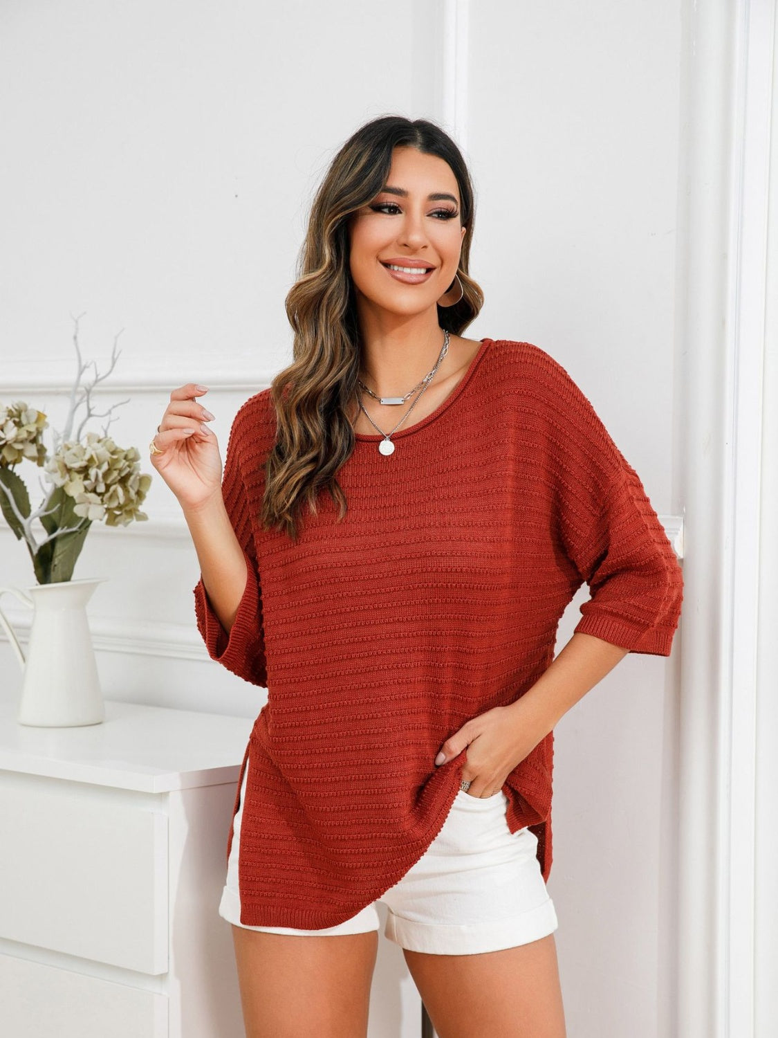 Rust knit sweater with boat neck, textured pattern, and slit hem detail.