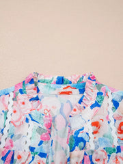 Cotton blouse with vibrant floral print, ruffled tie neck, and eyelet trim.
