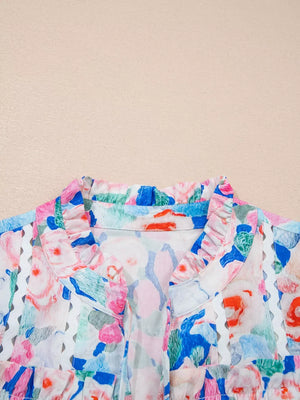 Cotton blouse with vibrant floral print, ruffled tie neck, and eyelet trim.