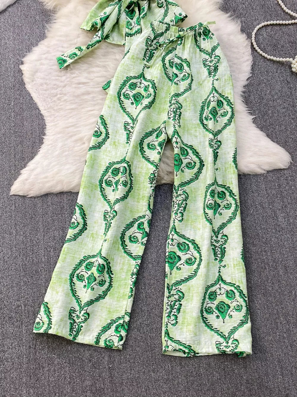 Green tropical print polyester two-piece set with wide-leg pants and belted detail.