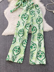 Green tropical print polyester two-piece set with wide-leg pants and belted detail.