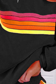 Black loungewear set with retro stripe detail in pink, orange, and yellow.