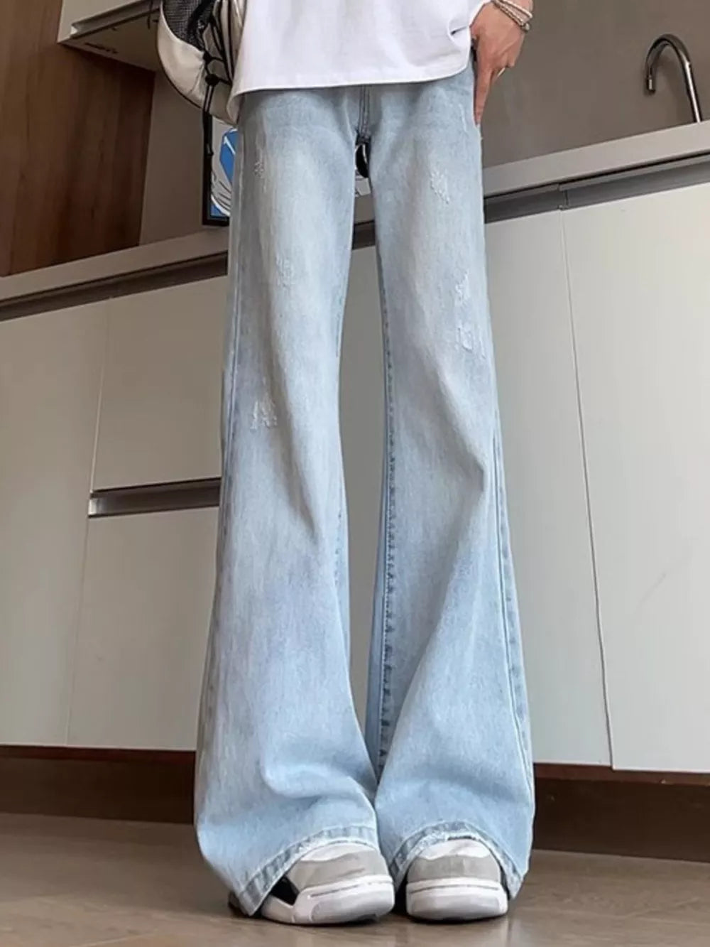 Distressed light blue full-length flare jeans for men with a cotton blend fabric.
