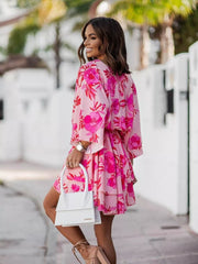 Tropical tiered mini dress in fuchsia pink with floral print, surplice neckline, and ruffled hem.