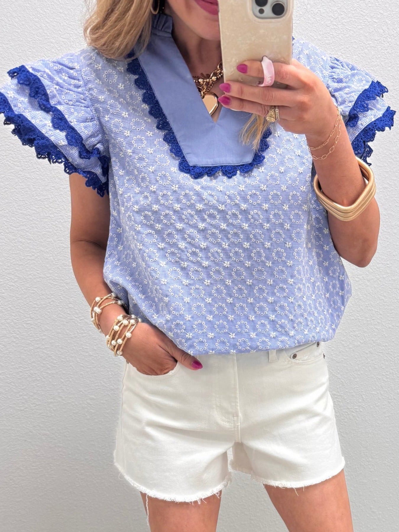 Light blue eyelet embroidered cotton blouse with flutter sleeves and lace trim.
