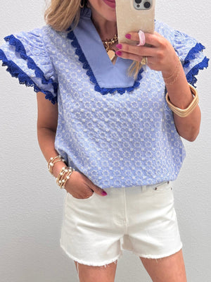 Light blue eyelet embroidered cotton blouse with flutter sleeves and lace trim.