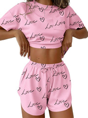 Pink pajama set with heart and love print, crop top with pocket, and drawstring shorts.