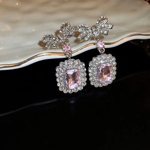 Silver bow crystal drop earrings with pink accents and rectangular pink gems.