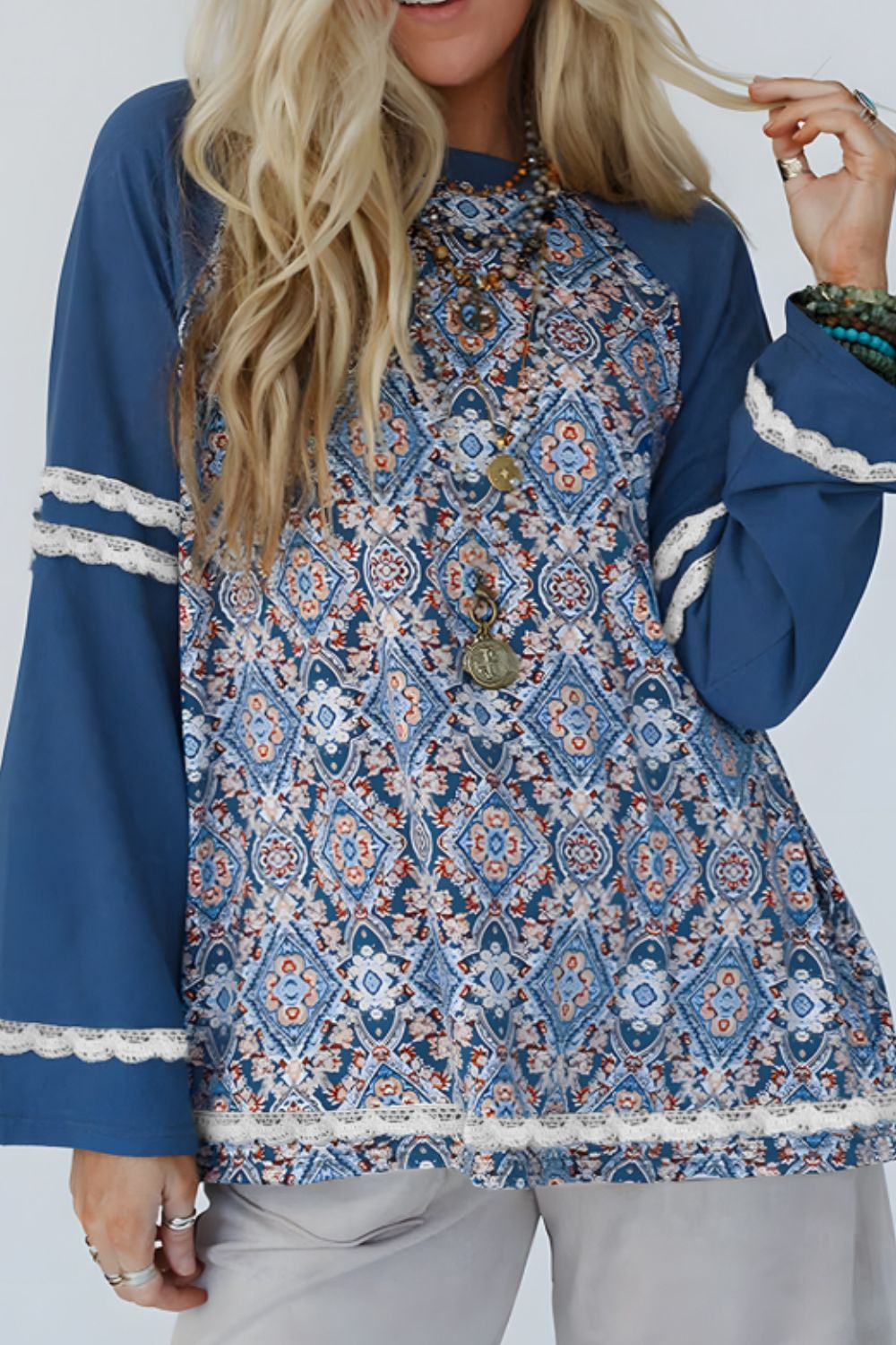 Bohemian print bell sleeve top in dusty blue with lace trim and ornate pattern.