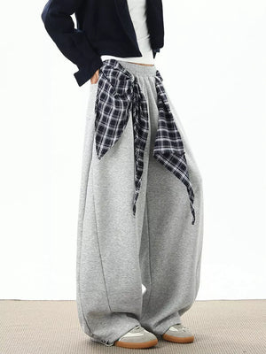 Relaxed fit grey sweatpants with wide legs and a plaid tie detail at the waist.