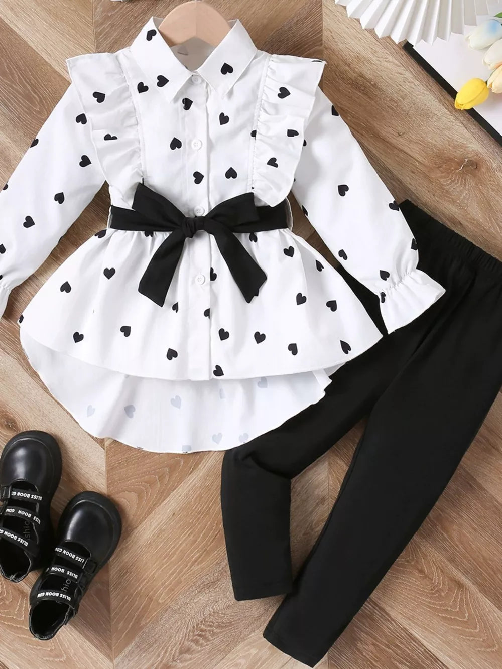 White heart print ruffle shirt with black bow and black leggings for toddlers.
