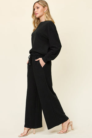 Black textured lounge set with crew neck sweatshirt and wide leg pants with drawstring waist