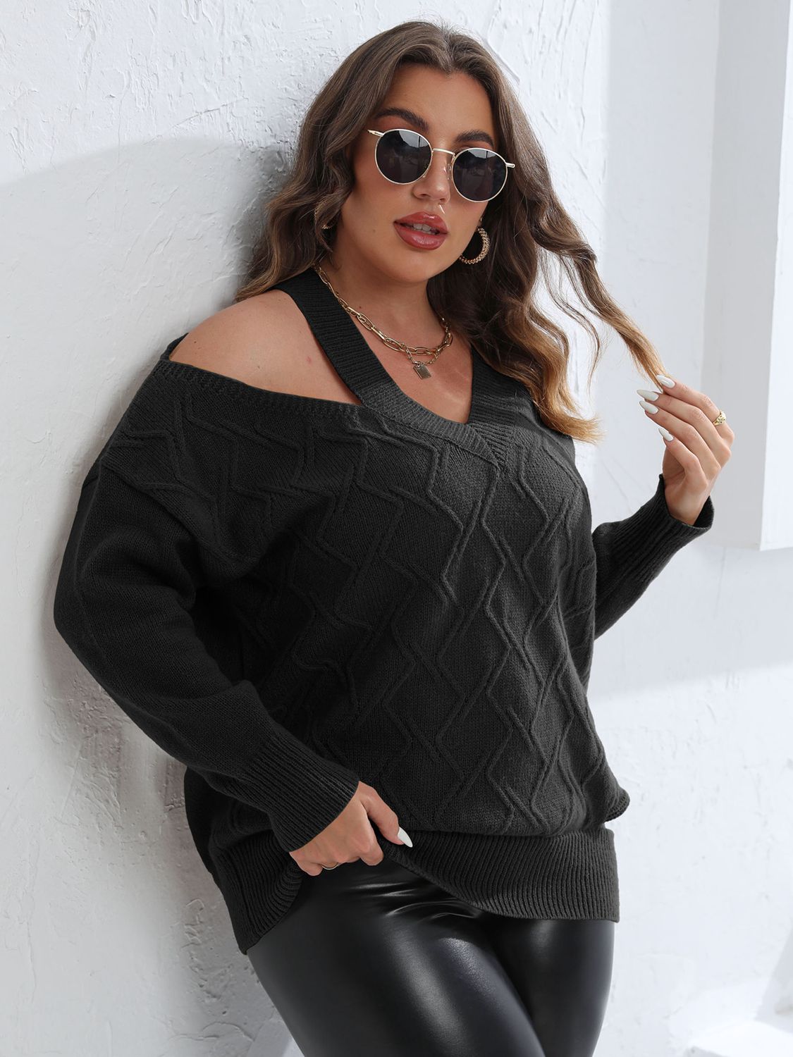 Black diamond knit sweater with asymmetric cold shoulder and V-neck detail.