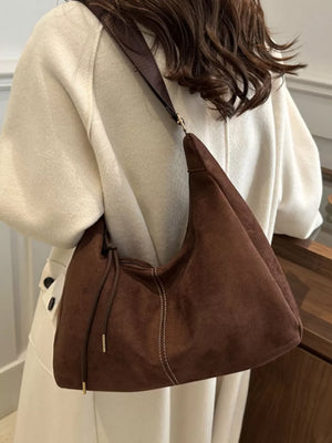 Brown suede crossbody bag with adjustable strap and drawstring detail