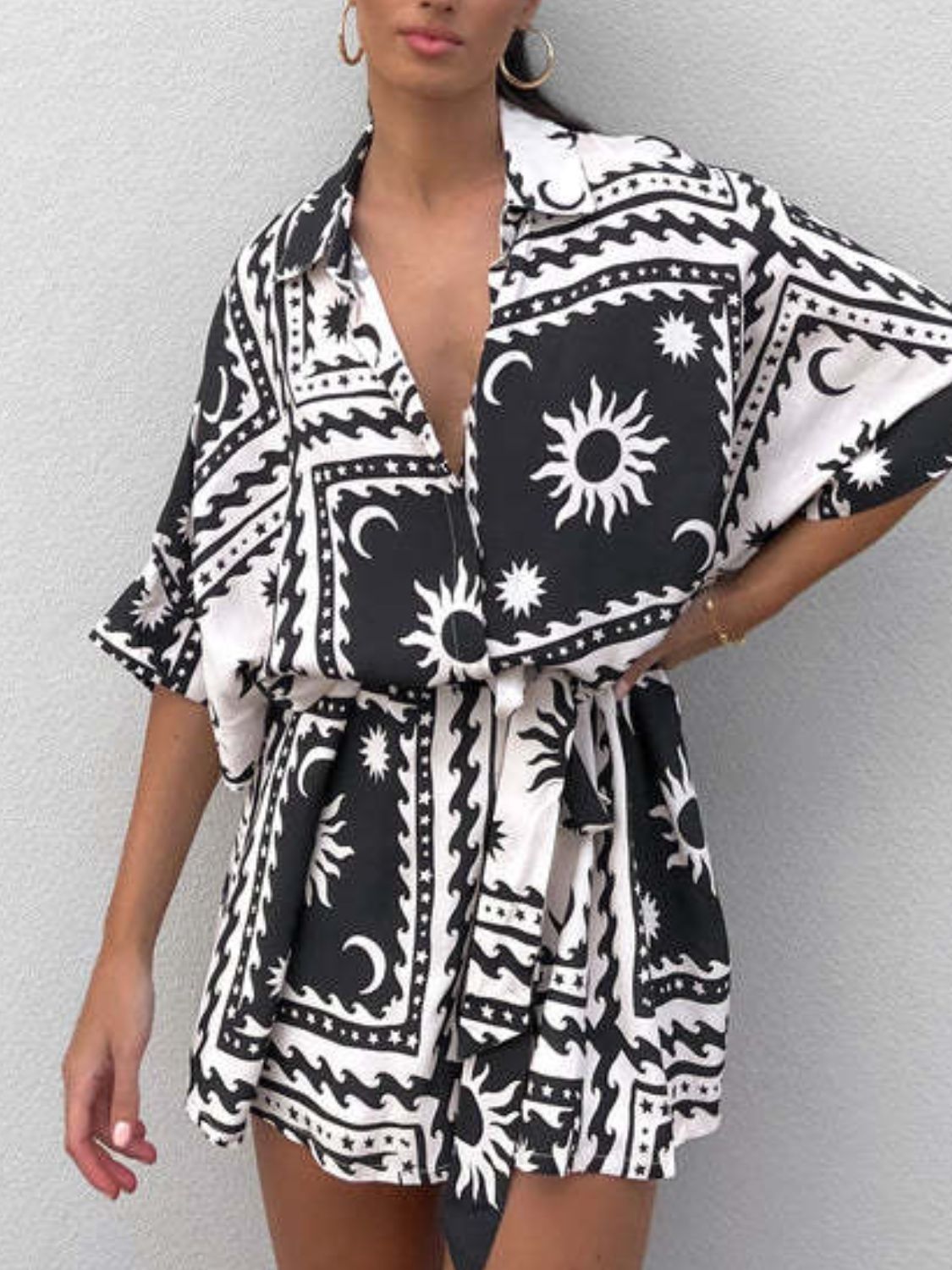 Black celestial print wrap romper with short sleeves and a tie waist.