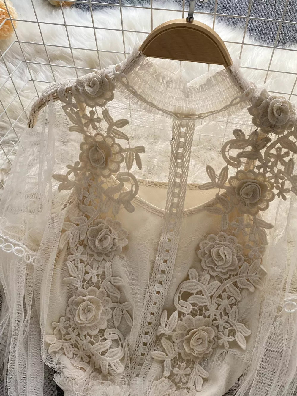 Creamy-white lace blouse with floral embroidery and ruffled collar, paired with cami.