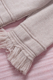 Eggshell knit sweater with off-the-shoulder neckline and fringe trim detail.