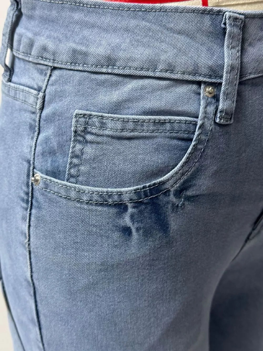 Light wash denim maternity jeans with button closure and wide leg cut.