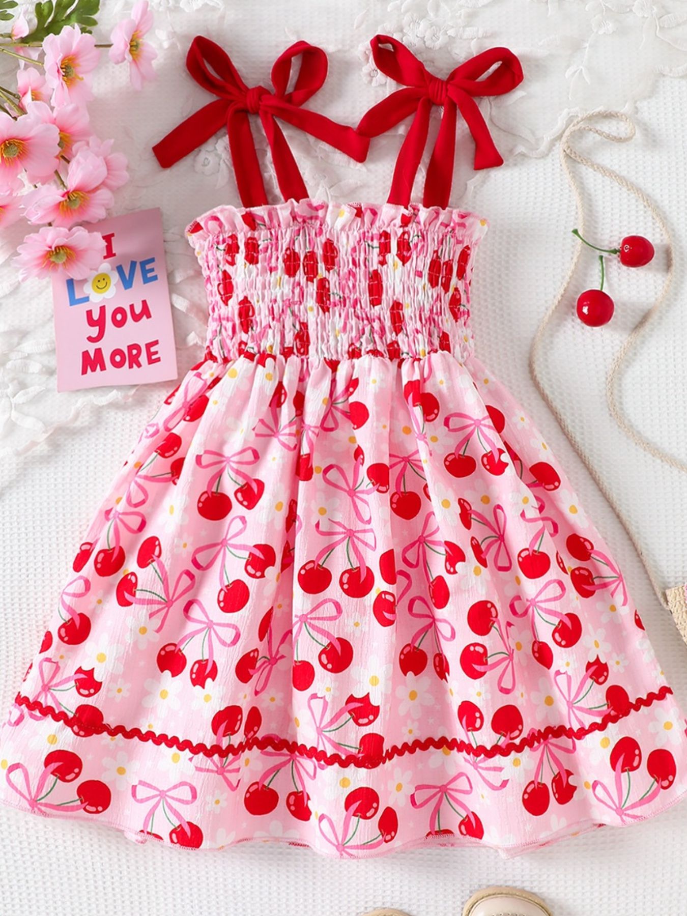 Pink cherry print smocked toddler dress with red bow straps and ruffled hem