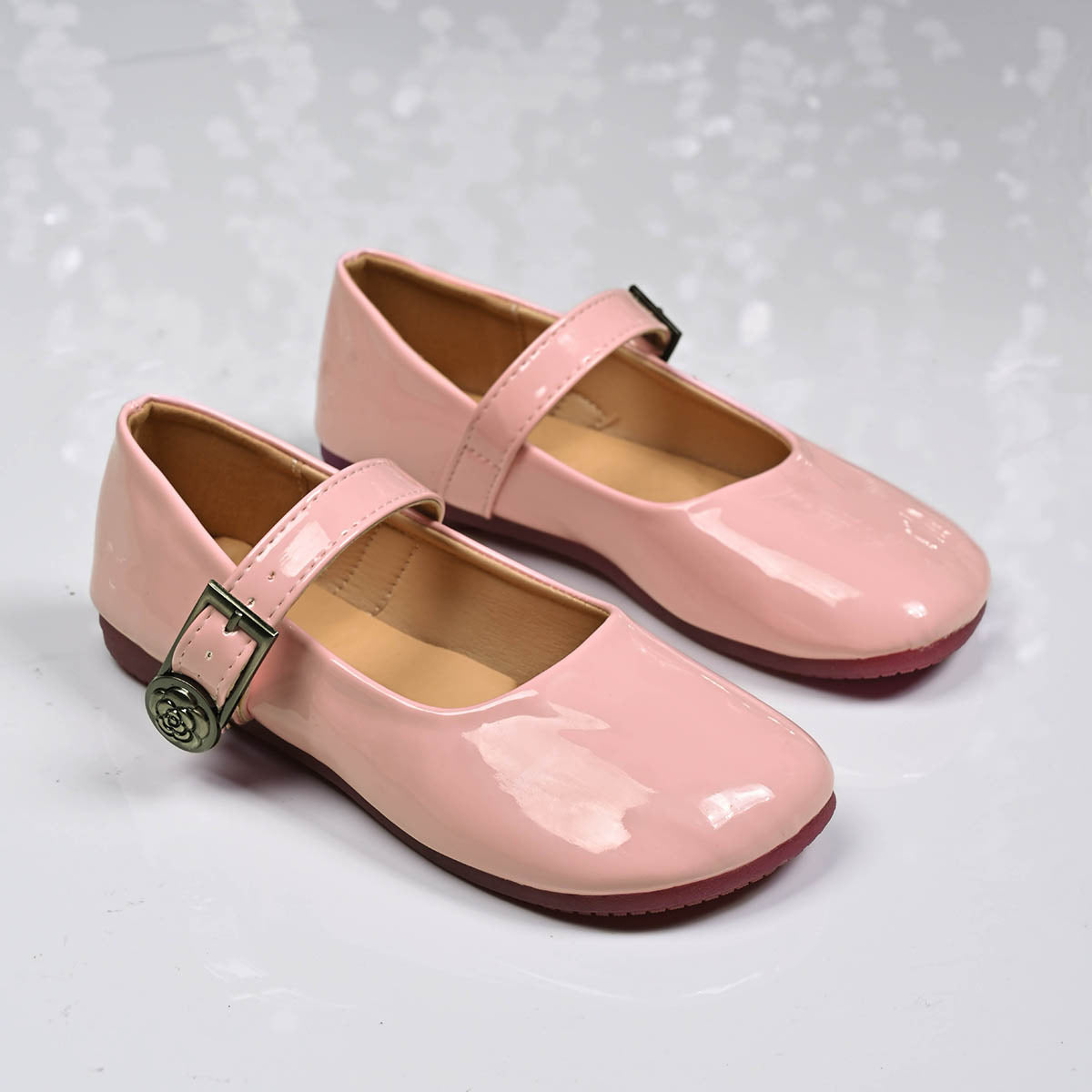 Pink patent buckle strap Mary Jane loafers with a rose detail buckle.