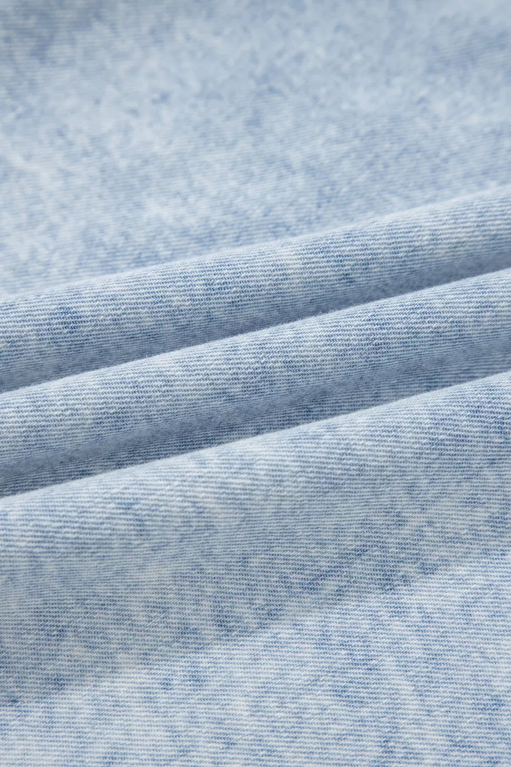 Light wash denim blouse with a textured, marbled pattern and visible weave.