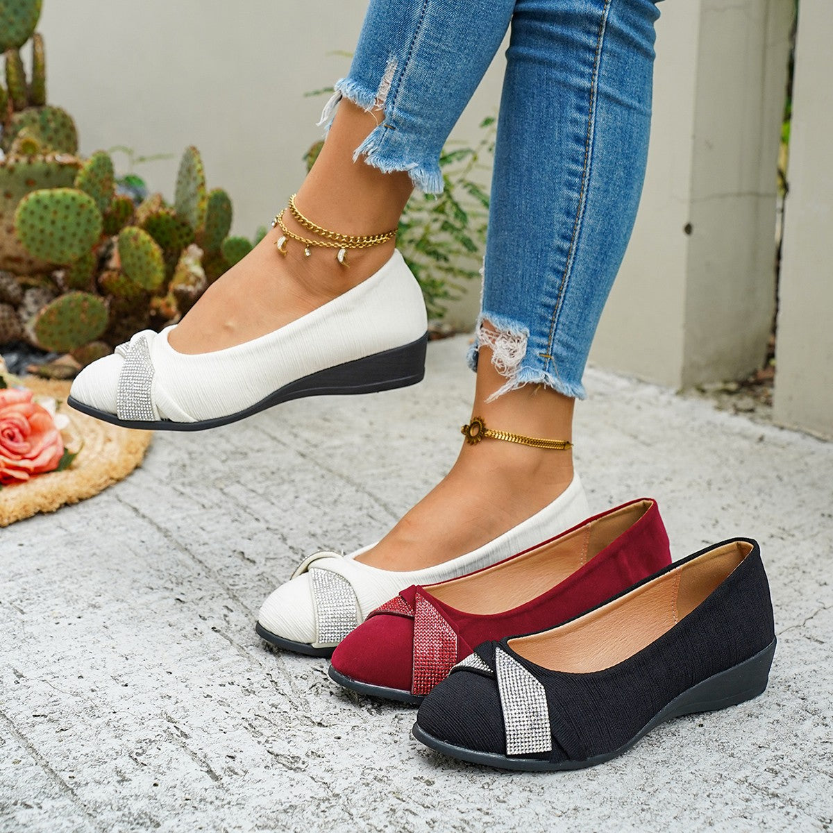 Rhinestone adorned slip-on wedge flats in red, beige, and black with textured fabric and bow detail.