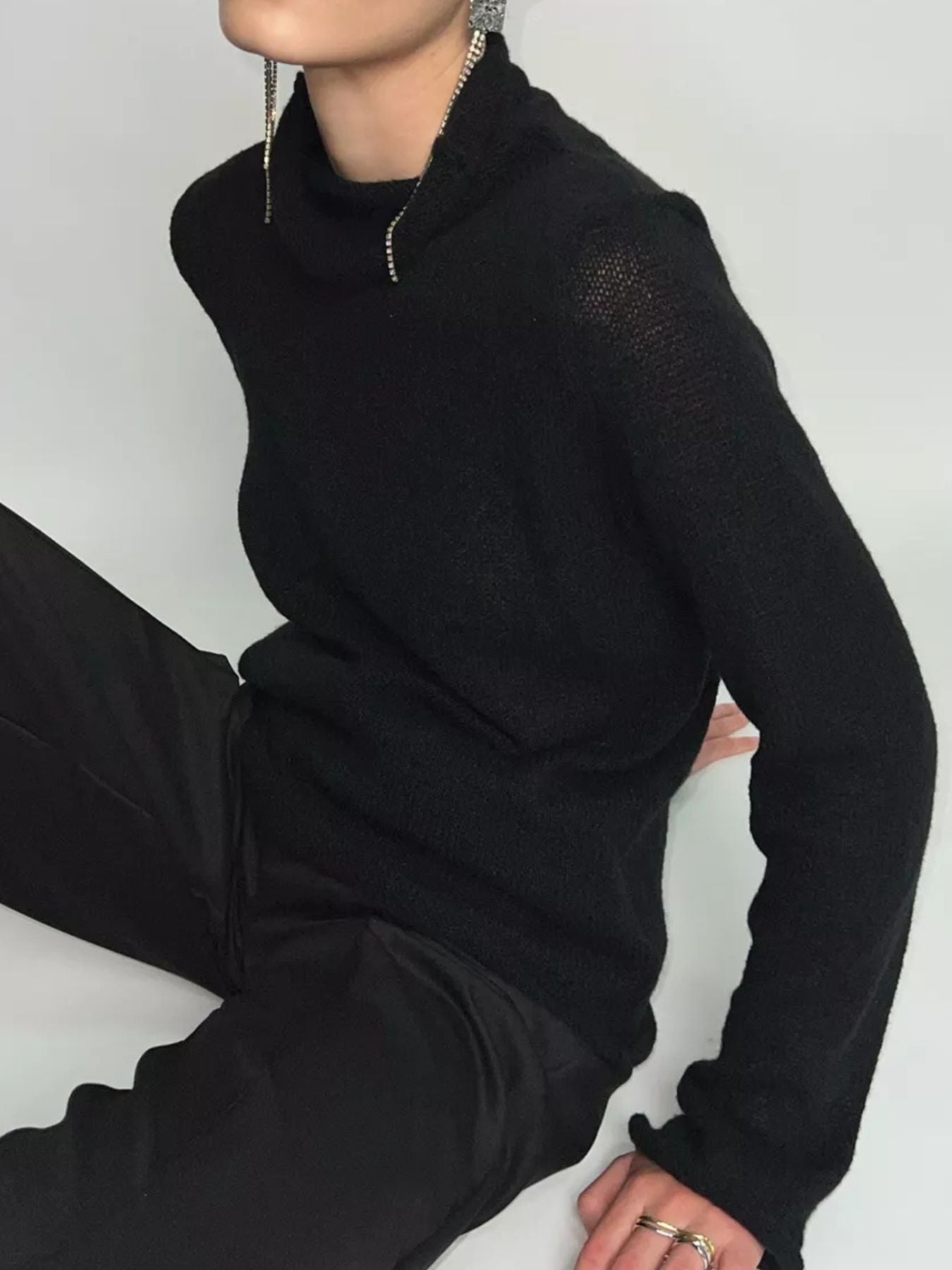 Black sheer mock neck knit sweater with draped fit and long sleeves.